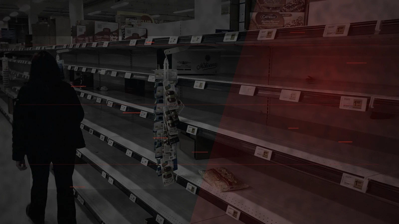 A shopper walking past severely depleted supermarket shelves during a sudden stock shortage